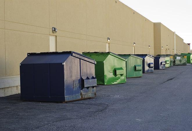 a construction worker empties a wheelbarrow of waste into the dumpster in Eidson